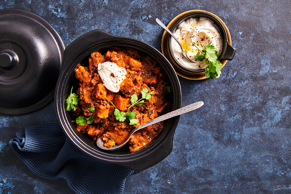 Dal makhani met zoete aardappelblokjes, koriander en crème fraiche