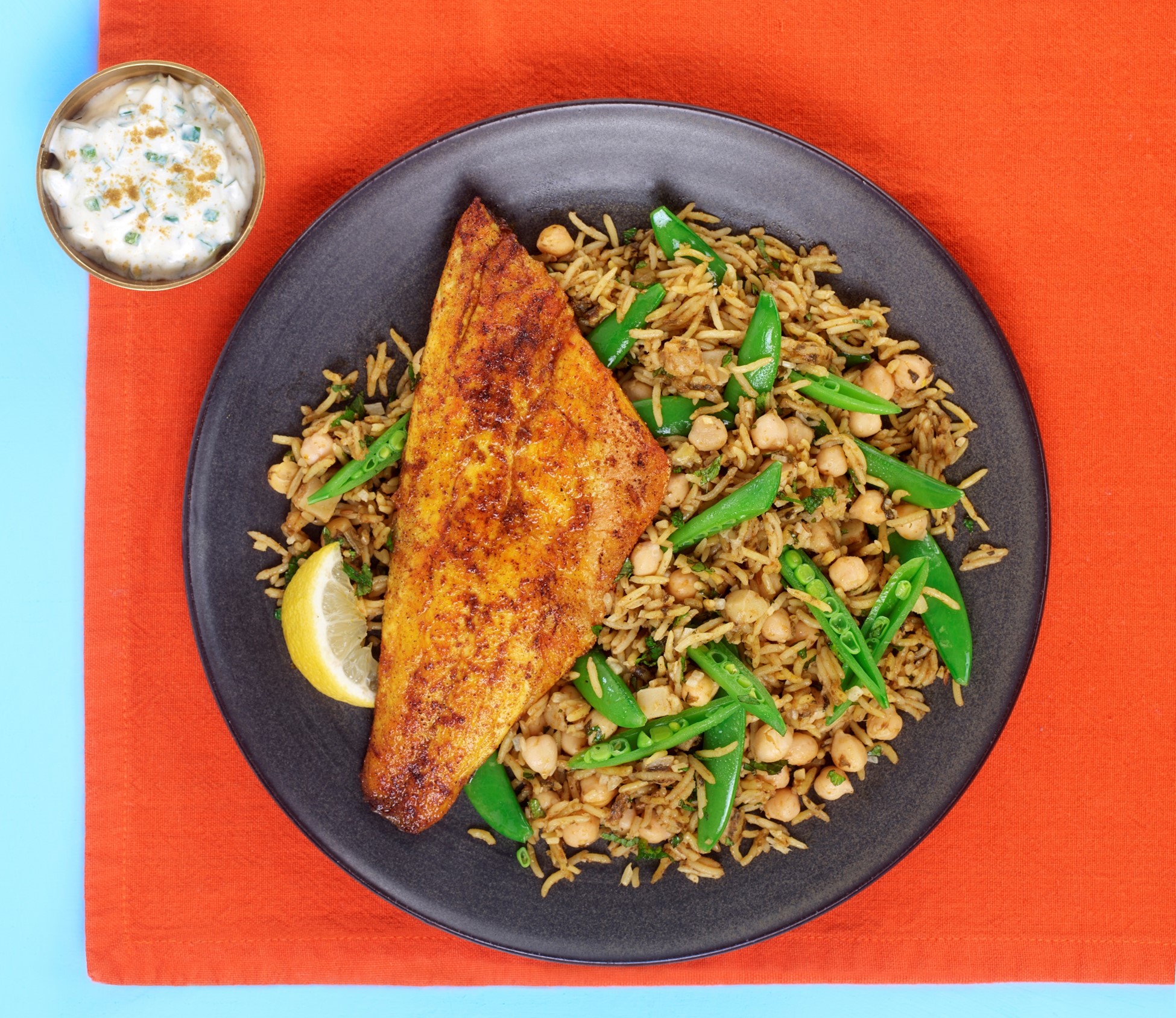 Spiced pan-fried sea bass with saag aloo chickpea rice and raita
